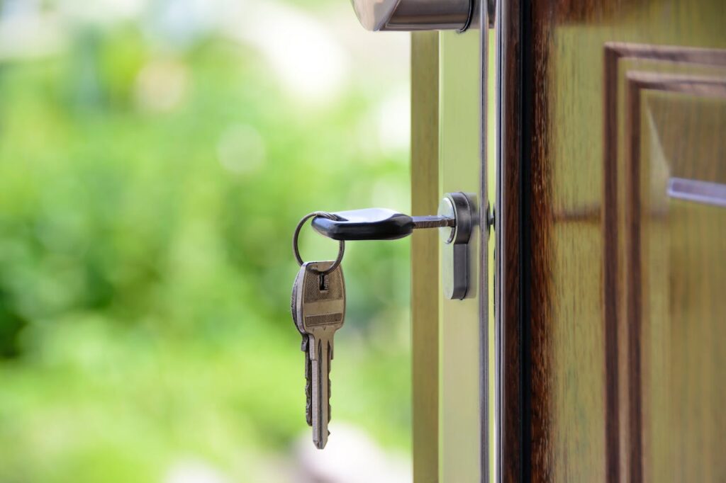 a key dangling from inside a lock on a wooden door